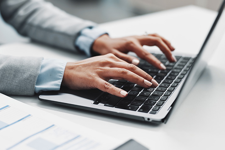 Eine Dame tippt einige Zeilen auf einem Laptop.